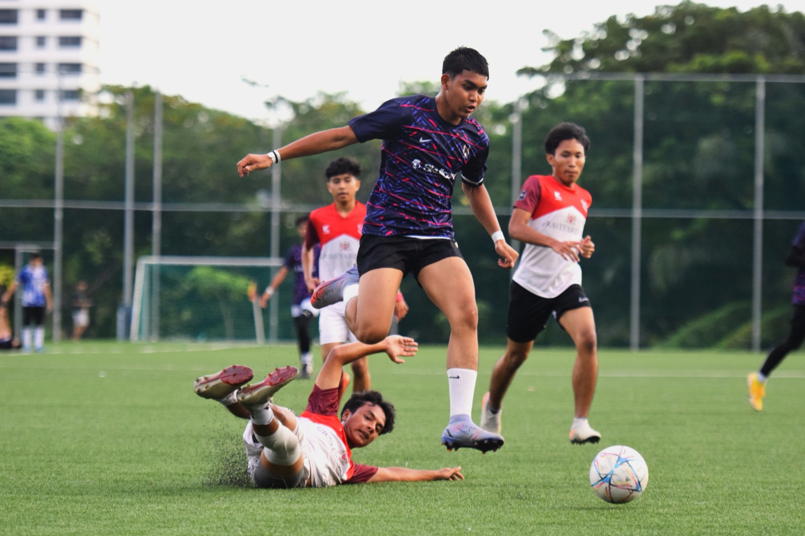 A footballer leaping over a sliding challenge