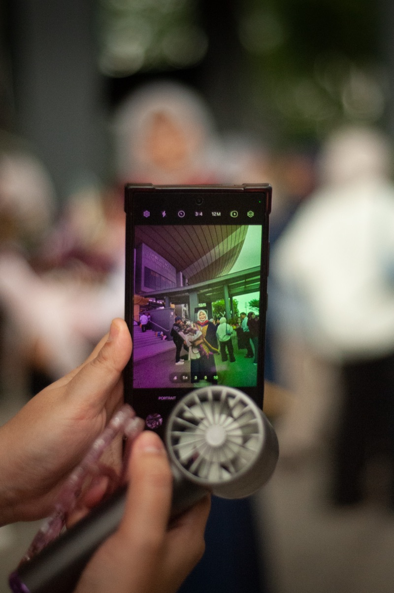 A phone screen framing a graduate being photographed at the ceremony
